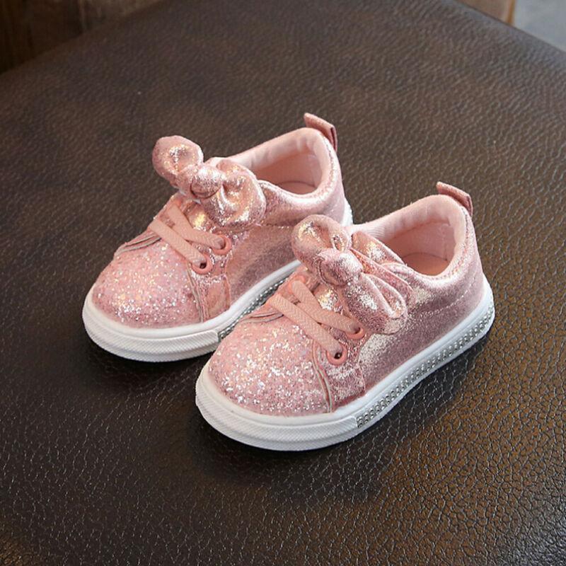 Girls pink glitter sneakers with bow embellishment, lace-up, white rubber sole.