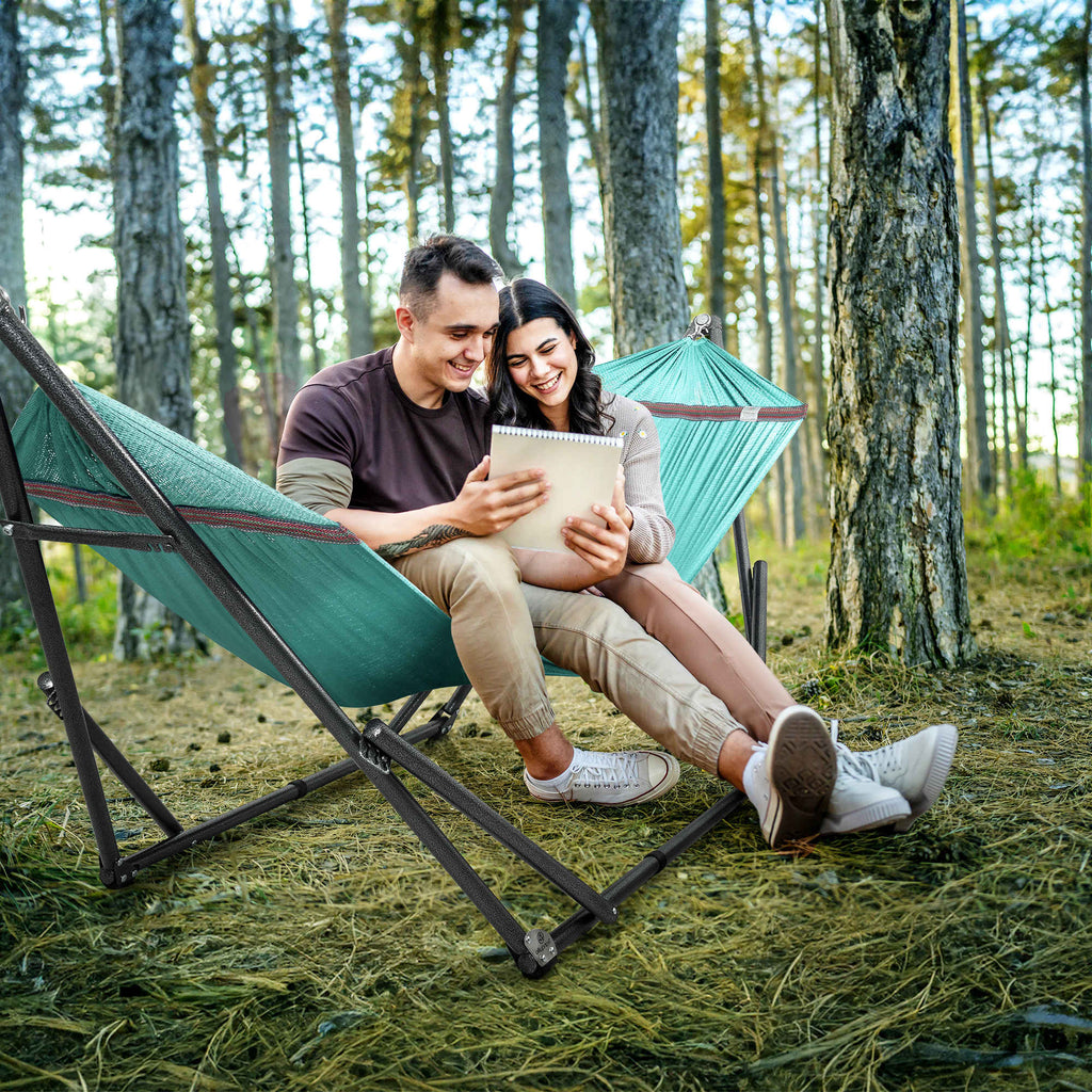 Teal hammock with black stand, two people sitting and reading outdoors