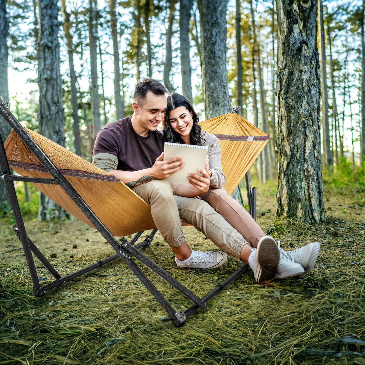 Yellow-orange hammock on black folding stand, two people relaxing outdoors