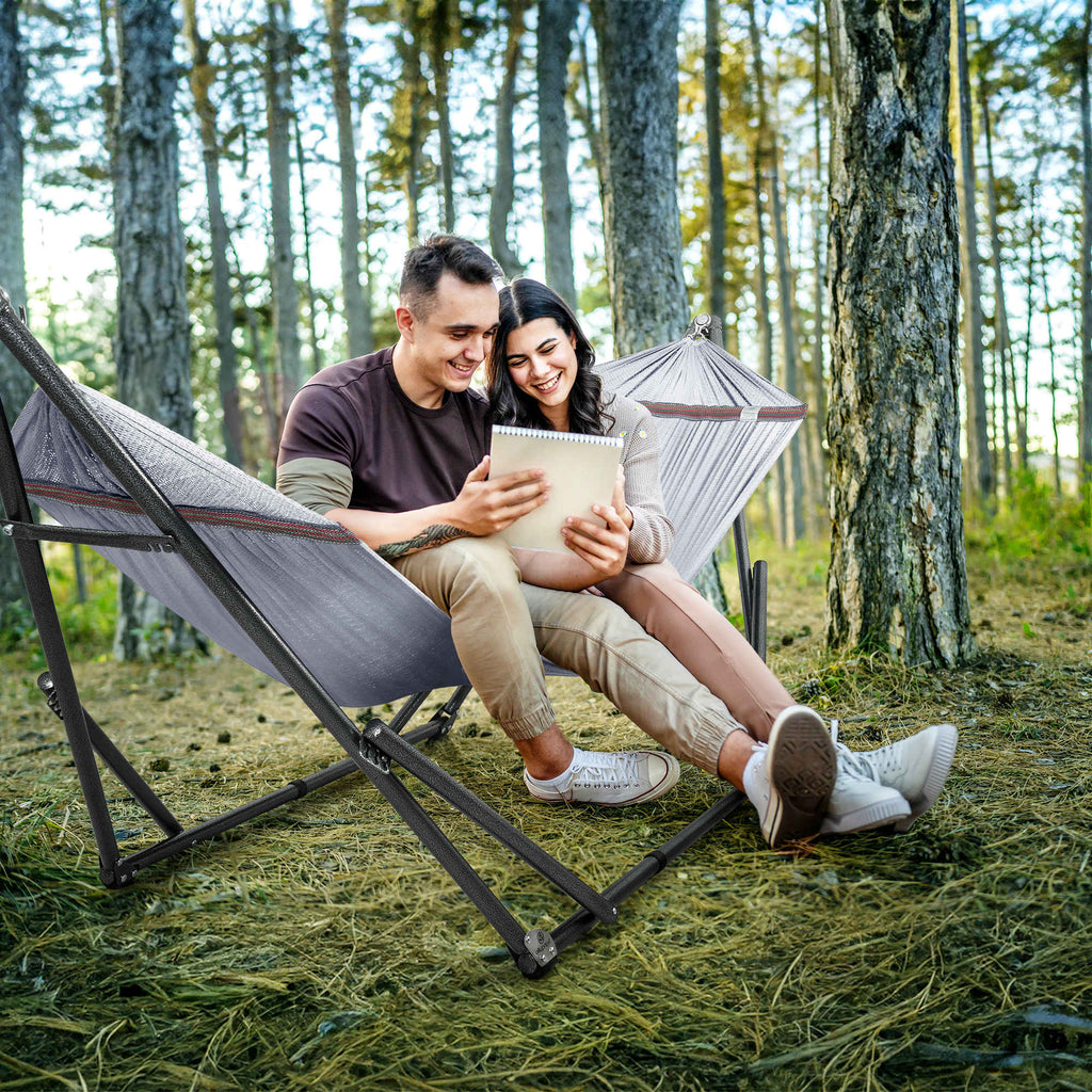 Two people seated together in a gray hammock on a black folding stand