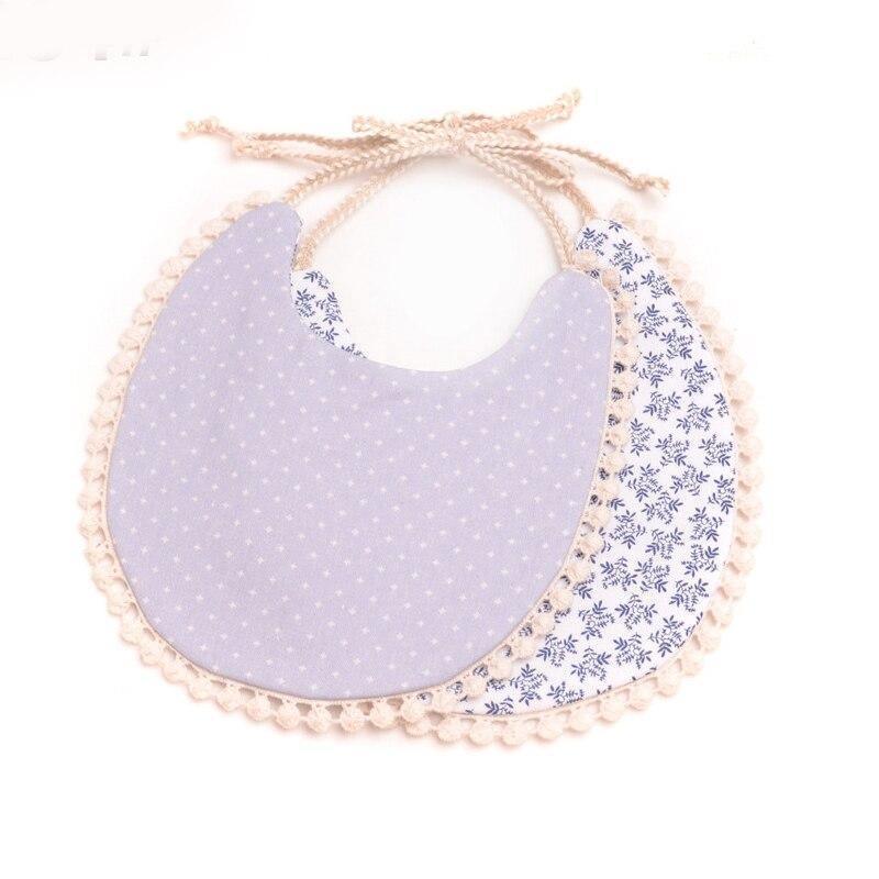 Purple dotted and blue floral double bib set with pom-pom trim and braided ties.