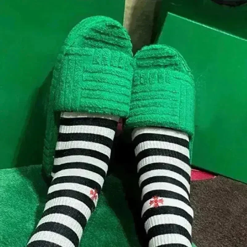 Green fuzzy open-toe slide slippers with thick sole and striped socks.