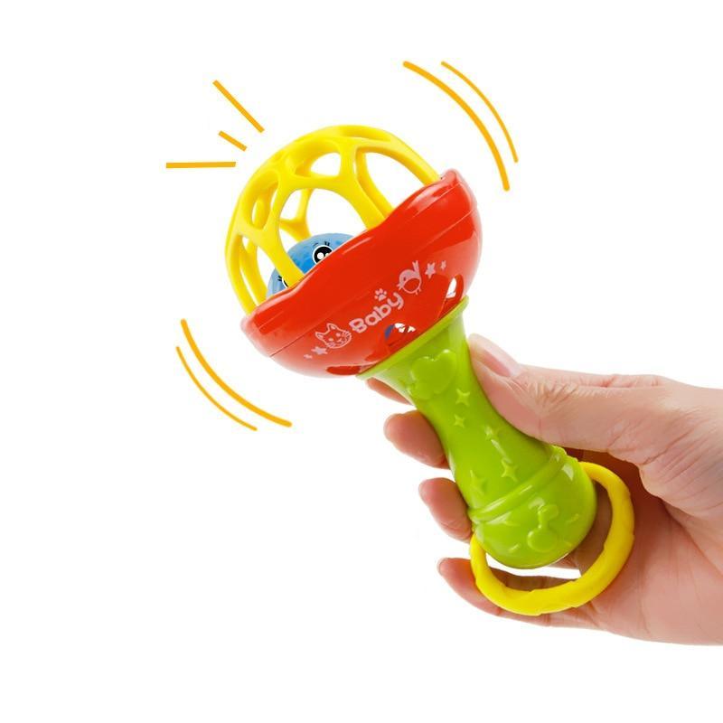 Baby plastic grasping rattle held in hand, red top with green handle