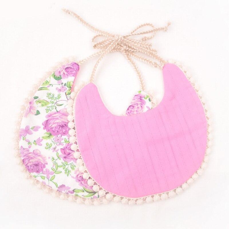 Infant bib set with pink solid front and purple floral back, tassel ties and pom-pom edge