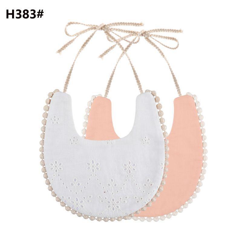 Double-sided cotton baby bib with tassel ties; white eyelet, peach, and light blush.