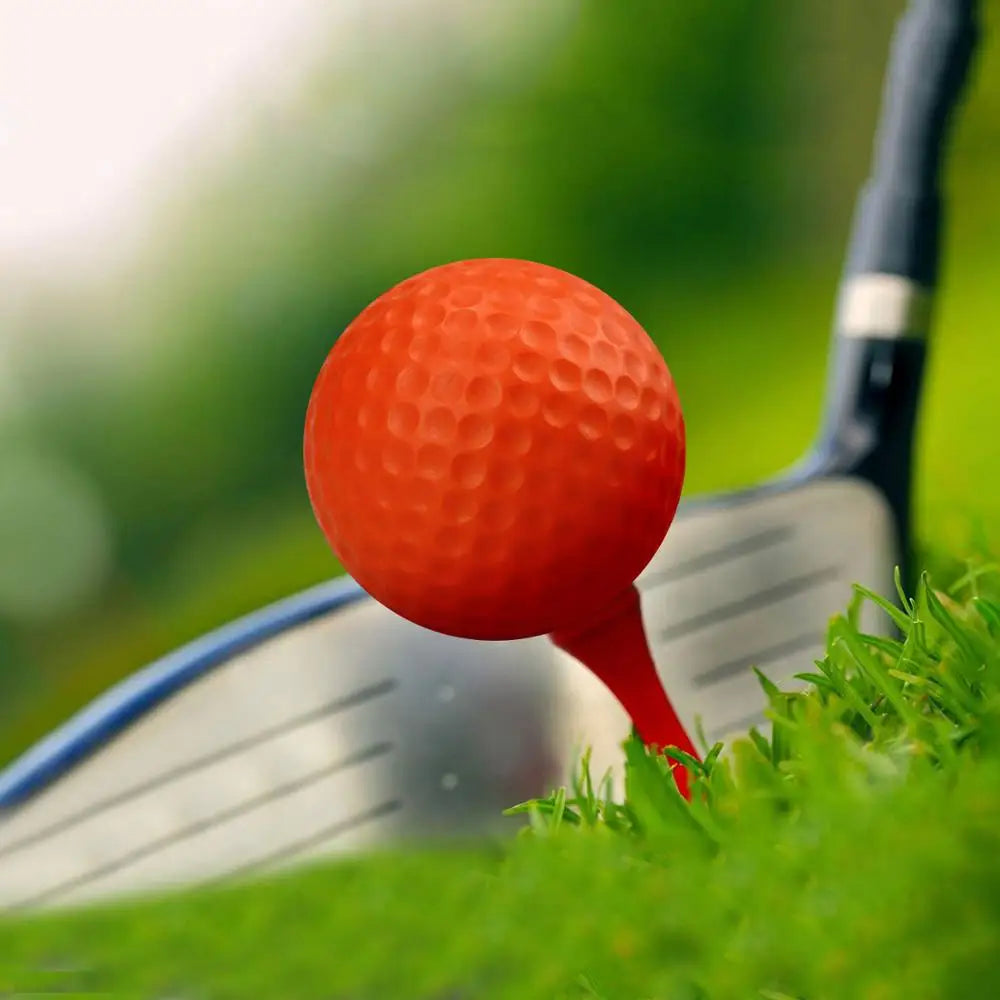 Orange foam golf practice ball in front of golf club, dimpled texture