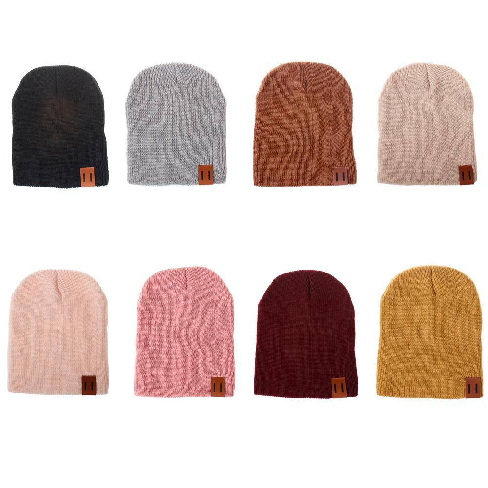 Multi-color knit beanie hat assortment with brown logo patch, foldover cuff