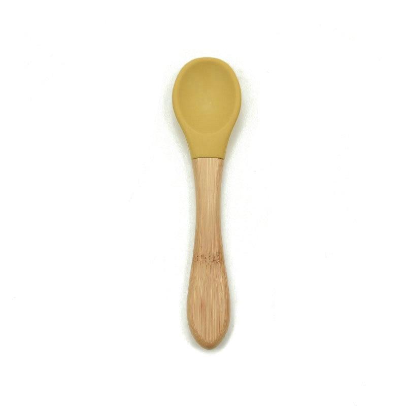 Baby feeding spoon with light wood handle and yellow silicone tip