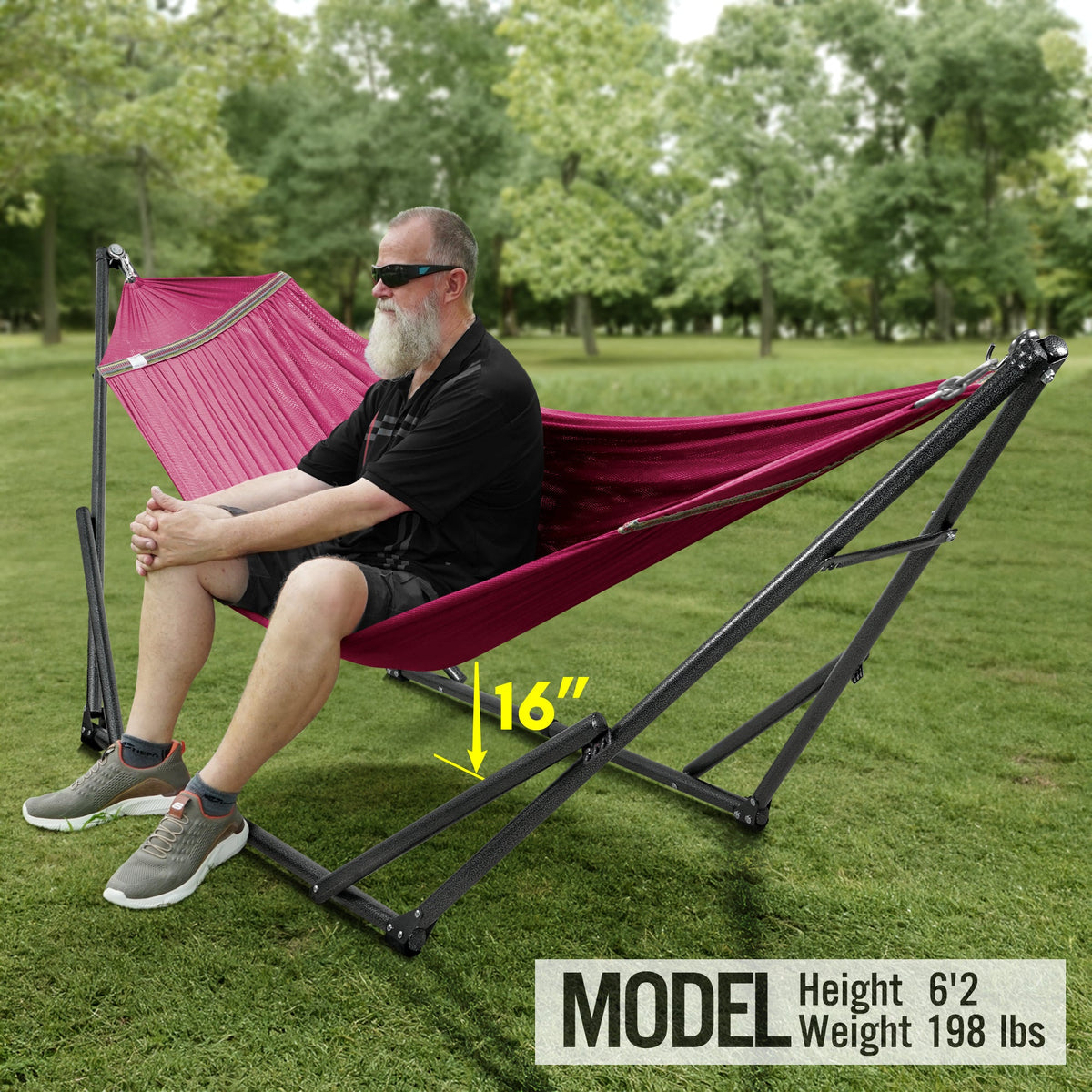 Maroon hammock on a black folding stand, with a person relaxing outdoors.