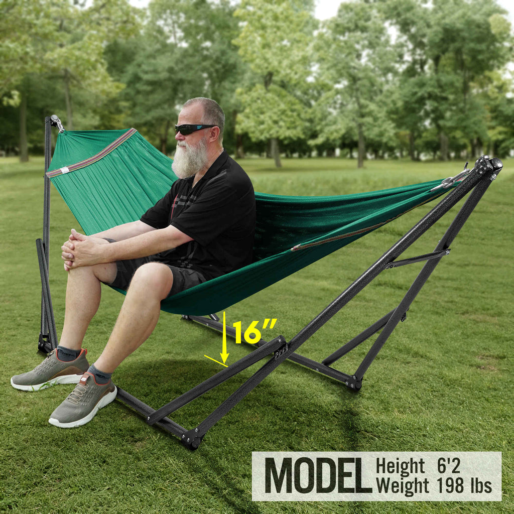 Teal hammock with black stand, seated person relaxing on outdoor lawn