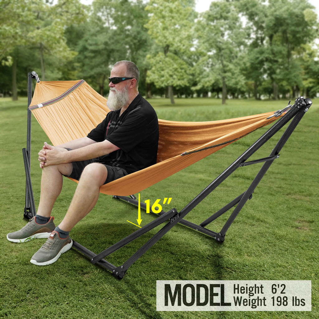 Orange hammock on black folding stand outdoors, one person seated and relaxing