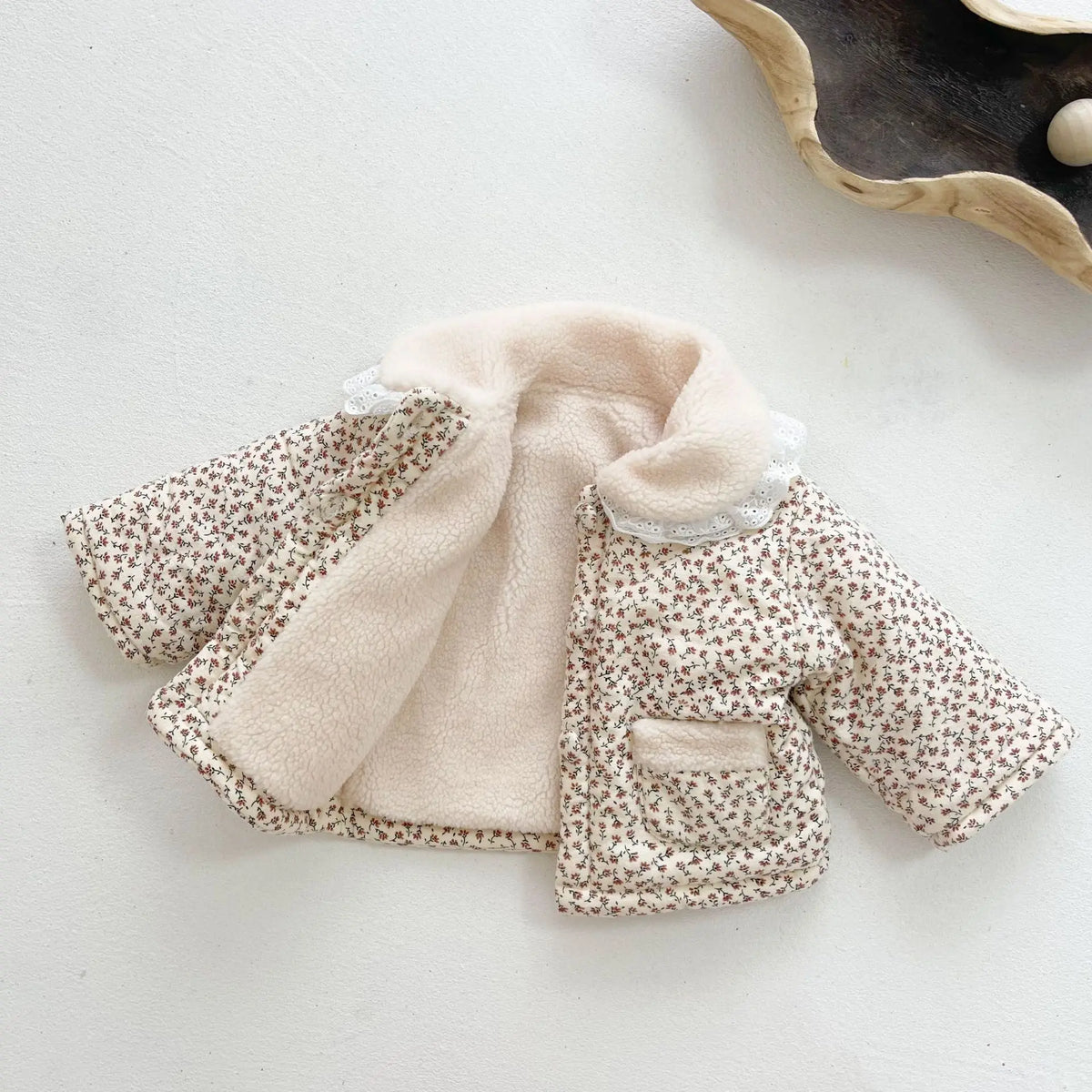 Flat-lay floral baby winter coat with cream sherpa collar and front pocket panels