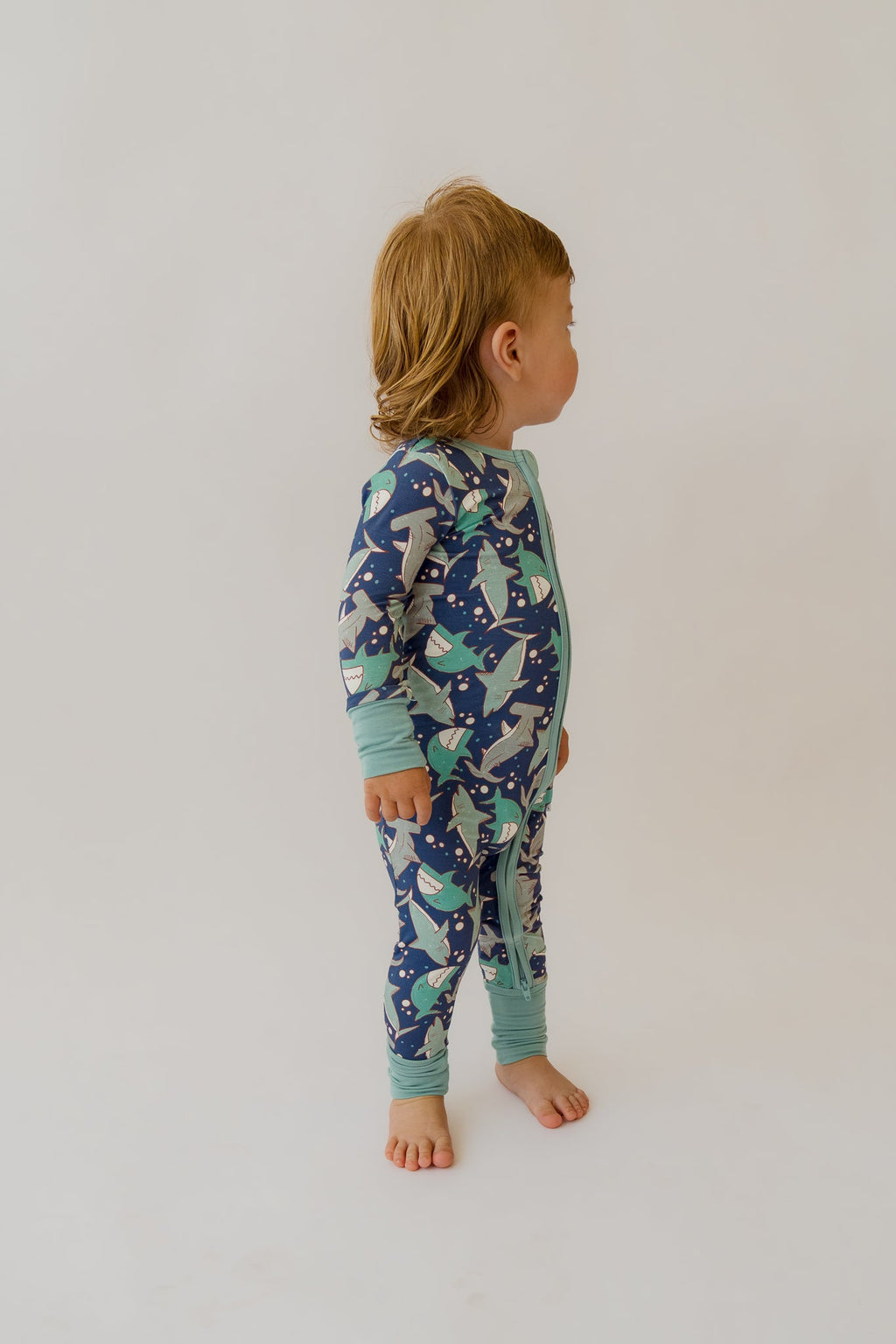 Back view of navy and teal shark-print baby overalls with zip front
