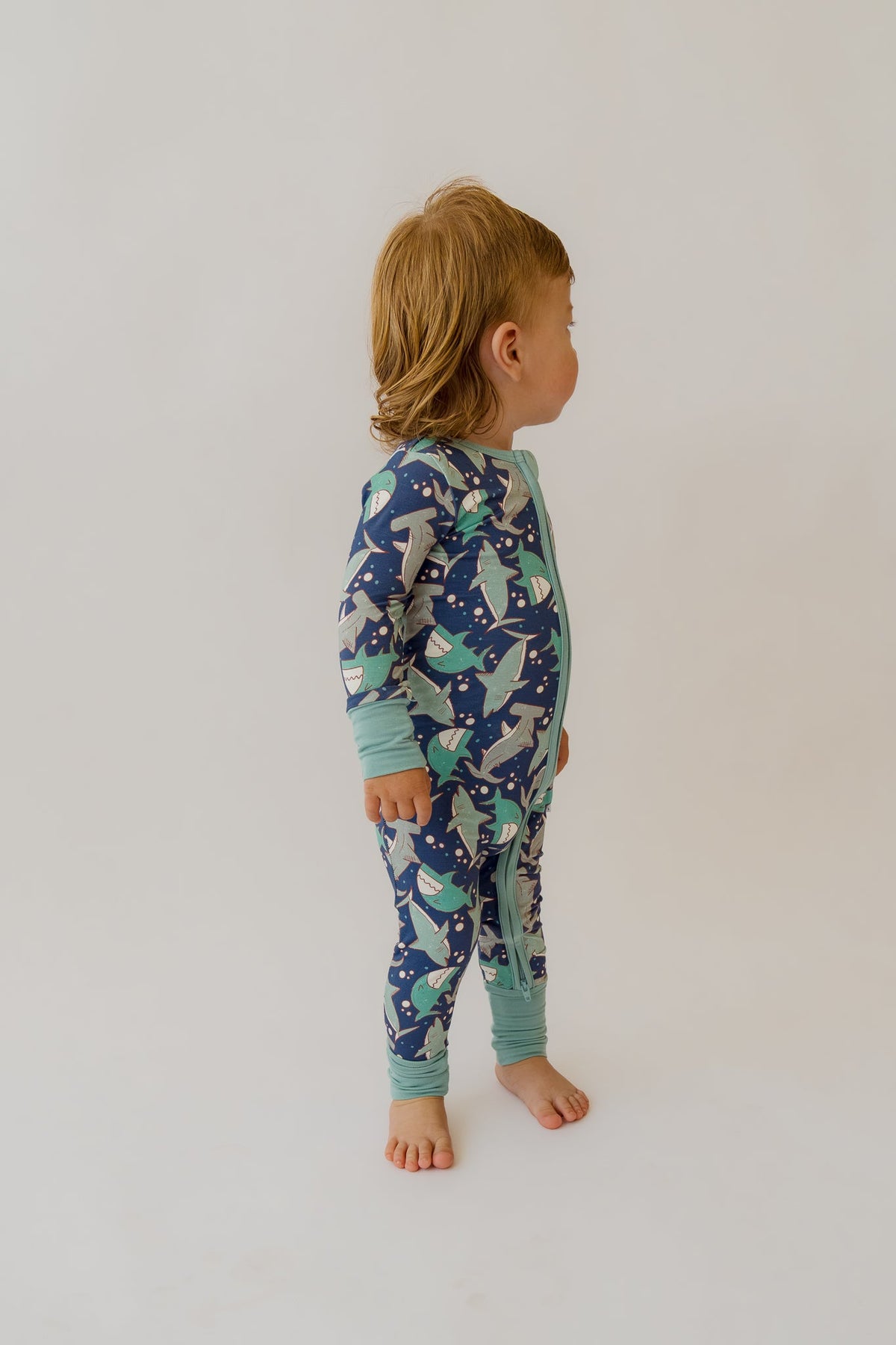 Back view of navy and teal shark-print baby overalls with zip front