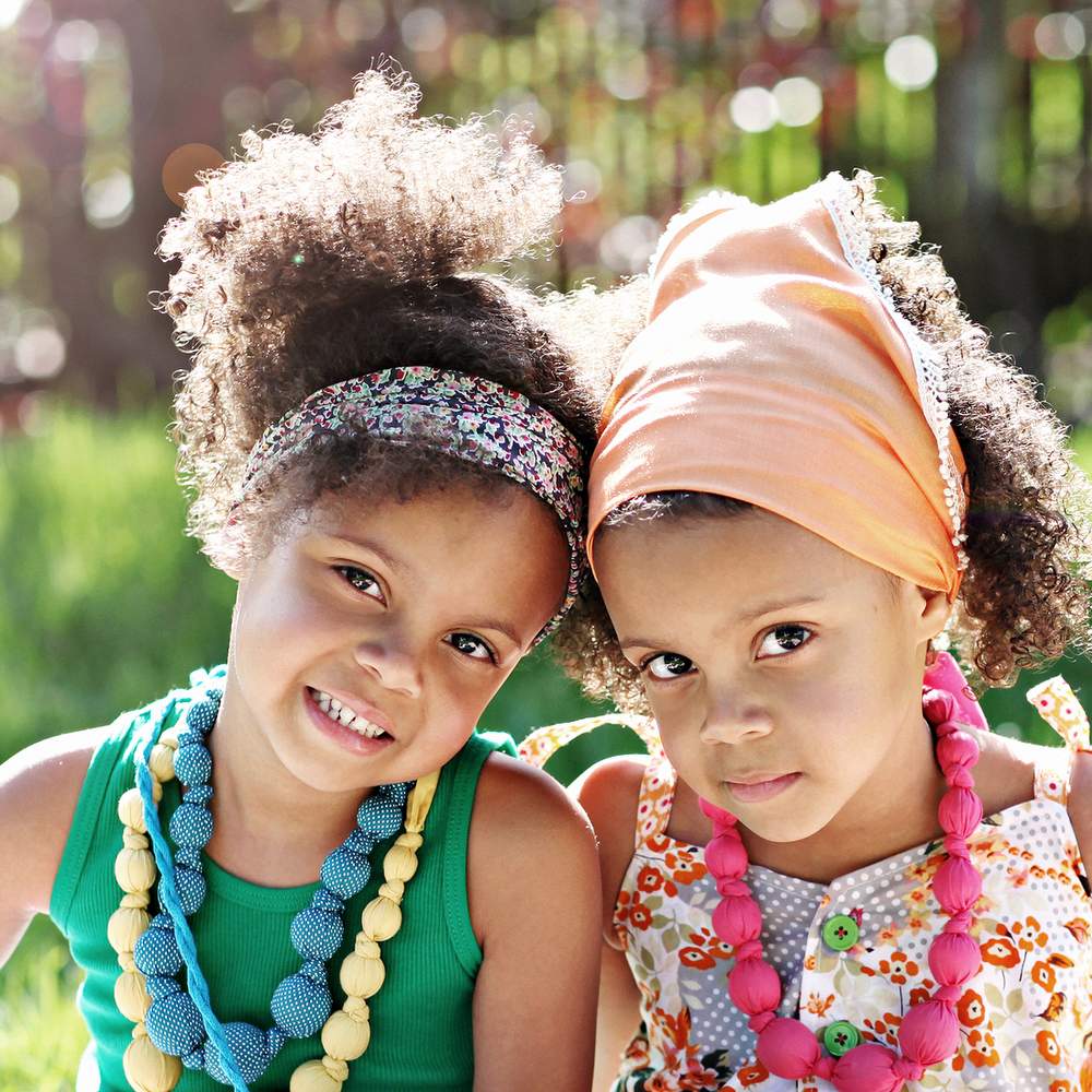 Kids wearing beaded fabric necklaces with multicolor polka-dot bead strands