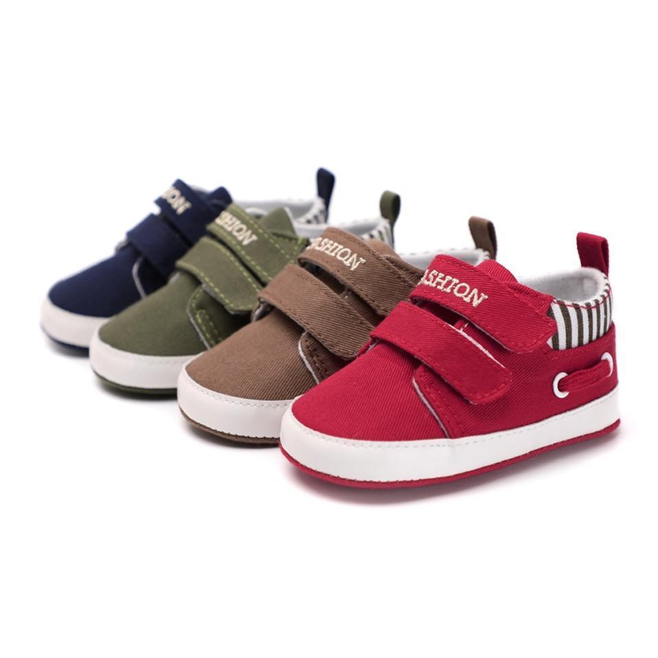 Four infant canvas sneakers in navy, olive, brown, and red, each with hook straps