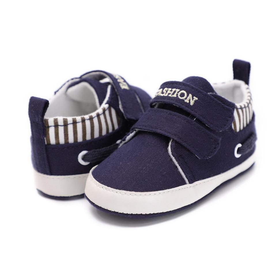 Pair of infant canvas sneakers, navy with hook strap, striped interior, white sole