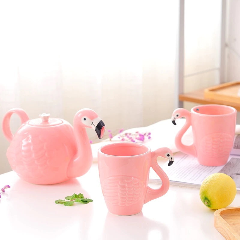 Pink ceramic flamingo teapot and mugs arranged on a table
