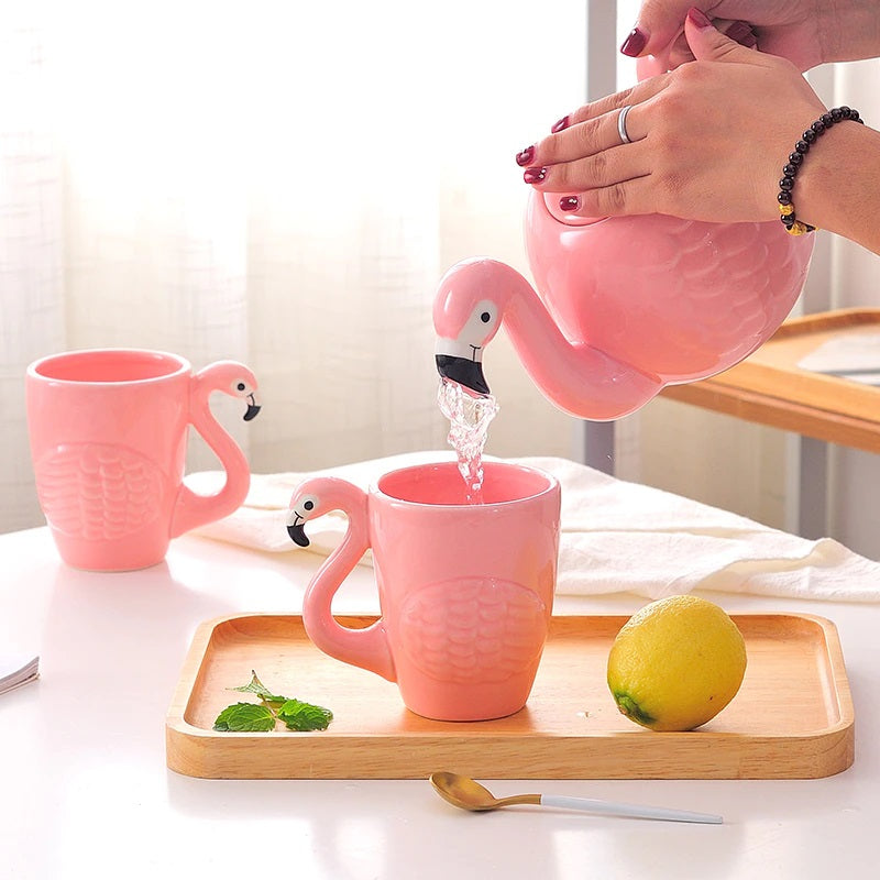 Pink flamingo teapot pouring into ceramic flamingo mugs on a wooden tray