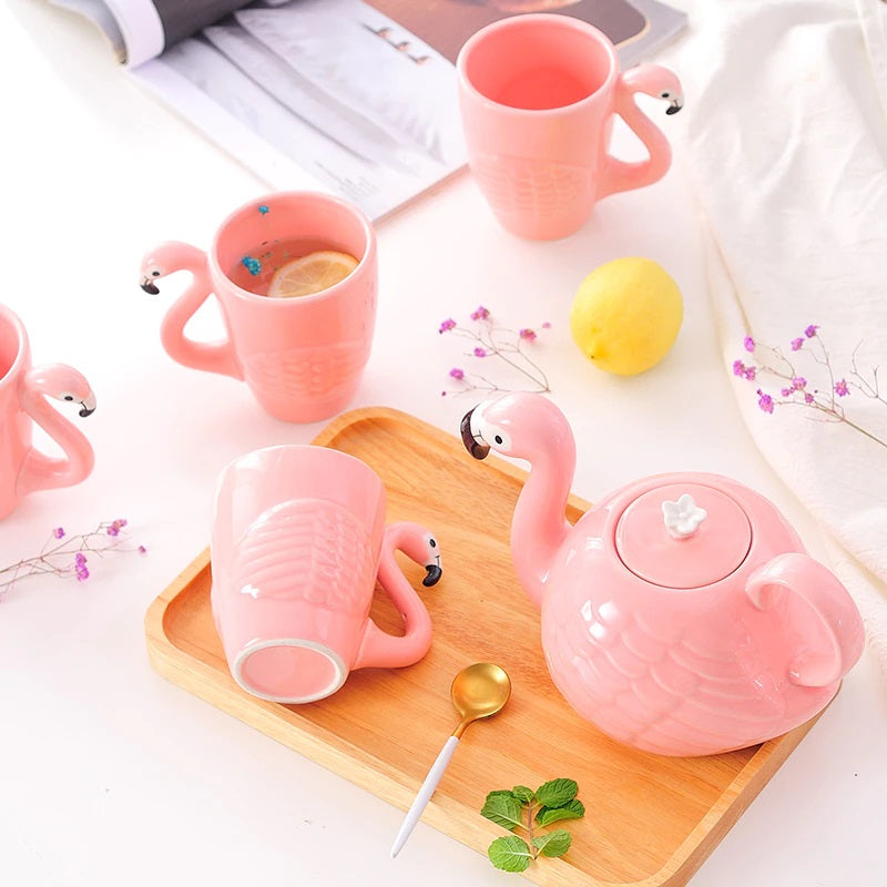 Pink ceramic flamingo mugs and teapot on a wooden serving board