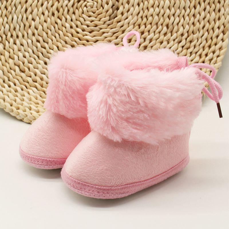 Pink fleece baby boots with fluffy cuff and lace tie, rounded toe first-walker style.