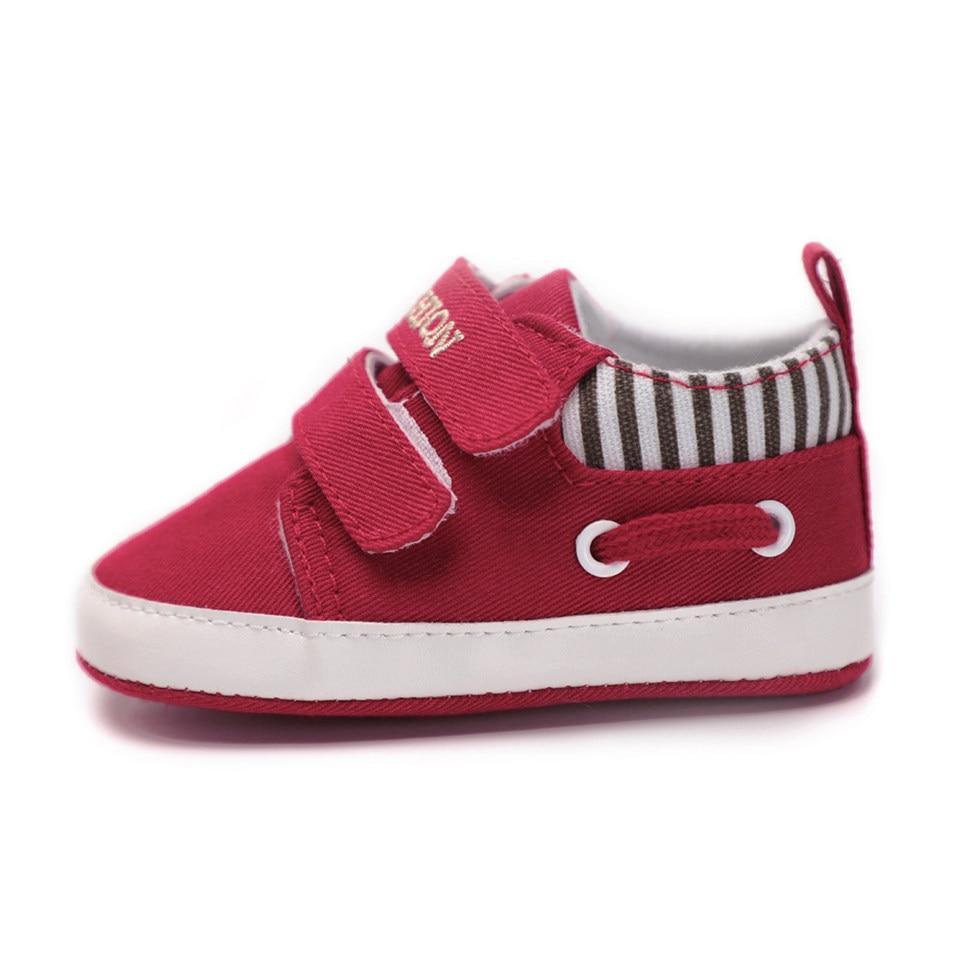 Infant canvas sneaker in red with two hook-and-loop straps, stripe collar, and white sole