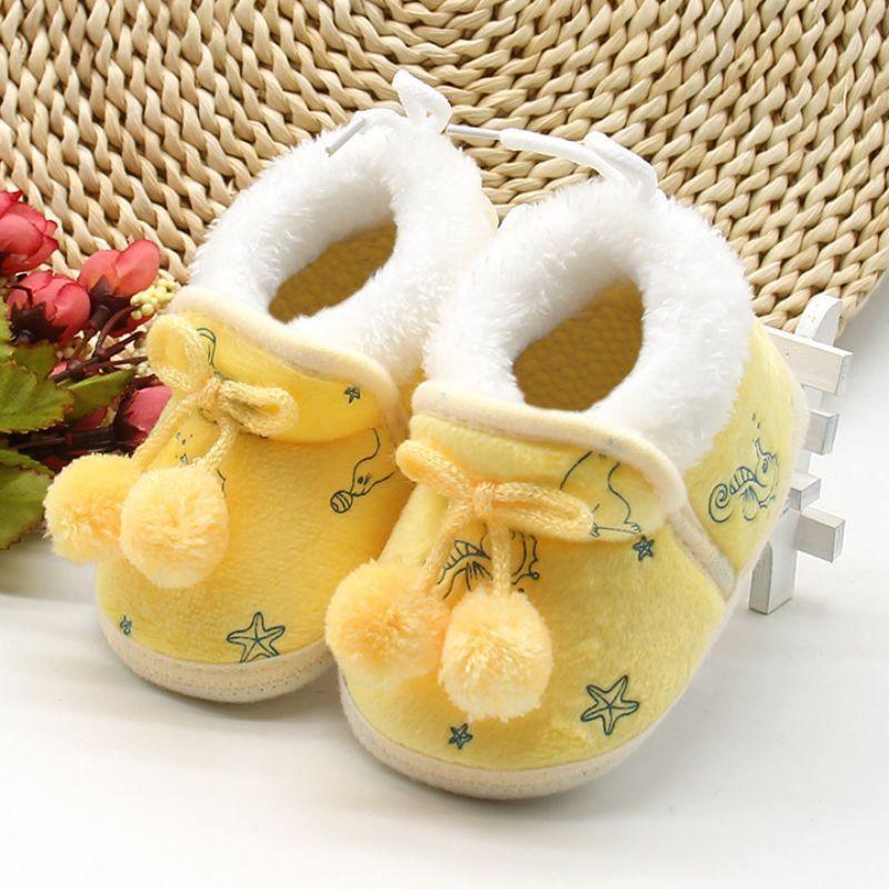 Soft baby boots in white and yellow with fuzzy lining, lace tie, pom-pom accents