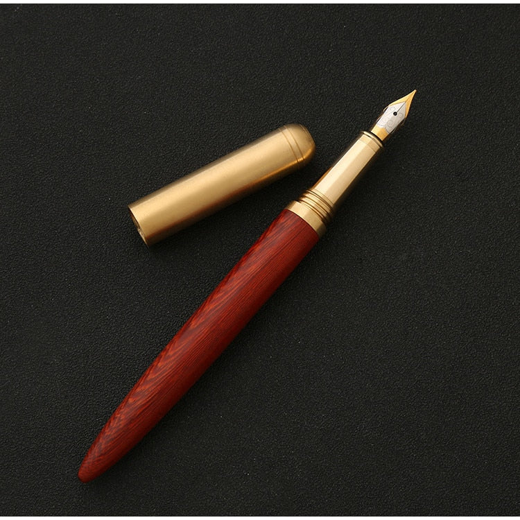 Handmade fountain pen with red wood barrel and brass accents, gold nib