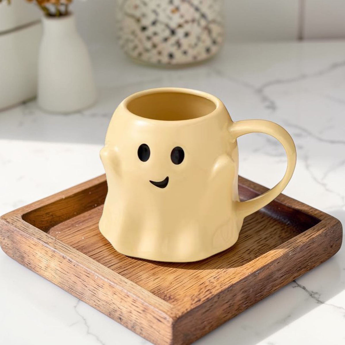 Yellow ghost-shaped mug with black eyes and a smiling face