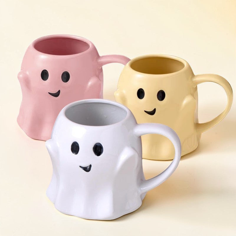Ghost-shaped ceramic mugs in pink, yellow, and white with smiling faces