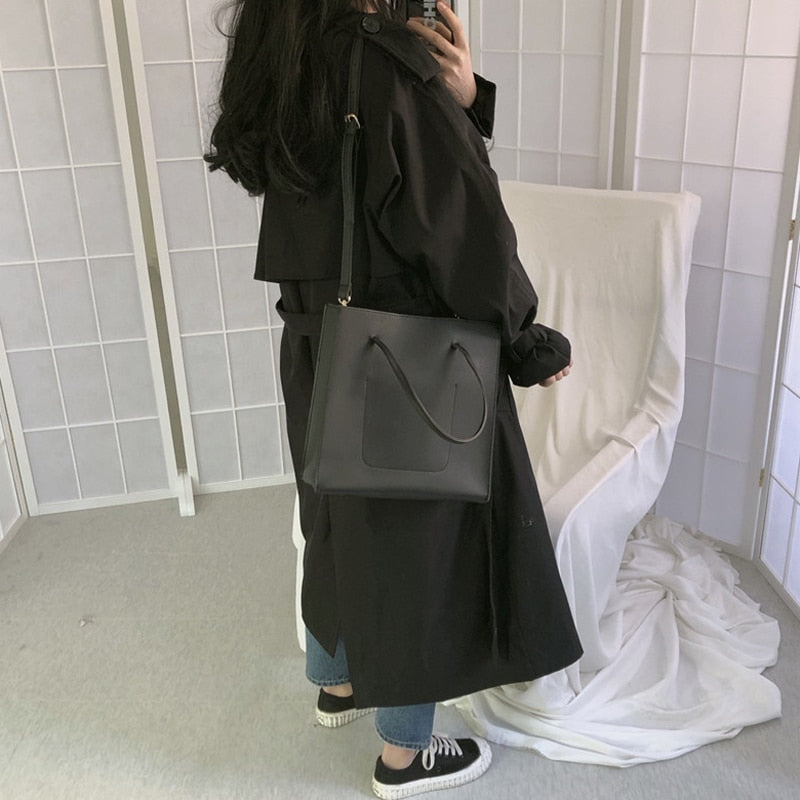 Black double-breasted long overcoat with button front and wide sleeves