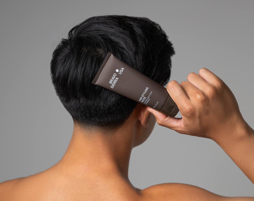 Hair styling paste applied to short black hair with a brown tube