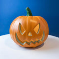 Orange jack-o’-lantern lantern decoration with carved triangle face cutouts
