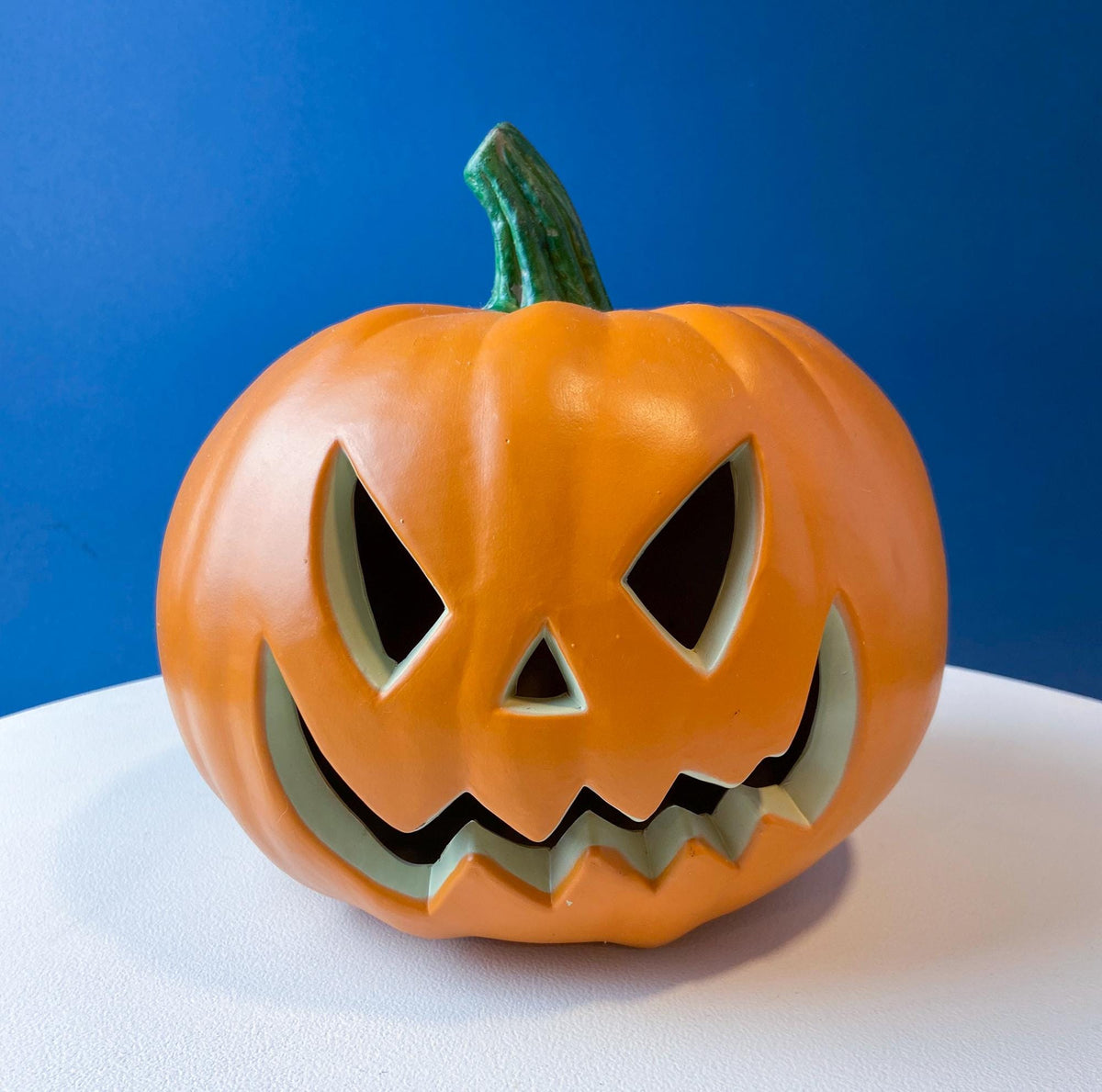 Orange jack-o’-lantern lantern with carved eyes and jagged grin cutouts