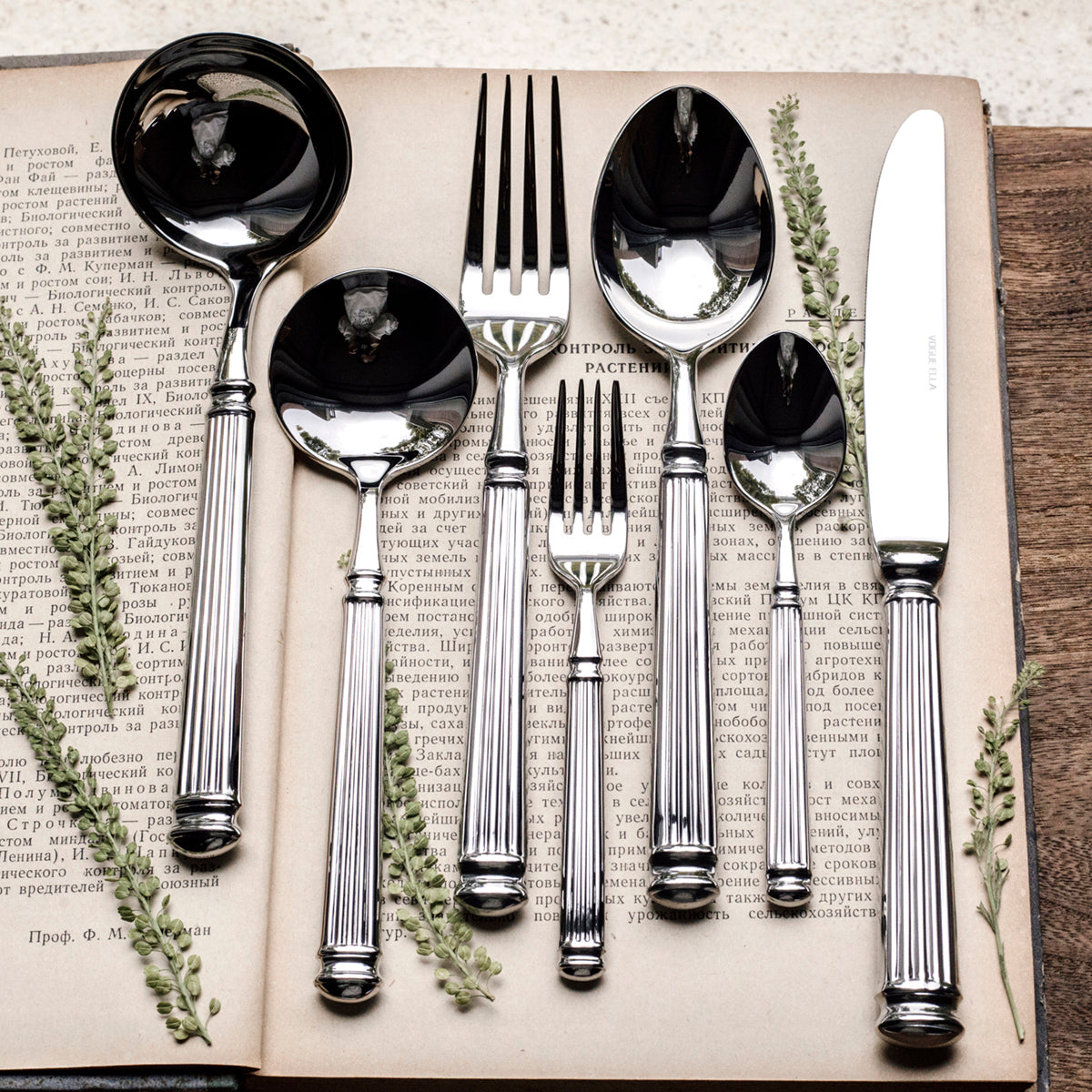 Silver-tone Roman column flatware set with spoons, forks, and knife in open box