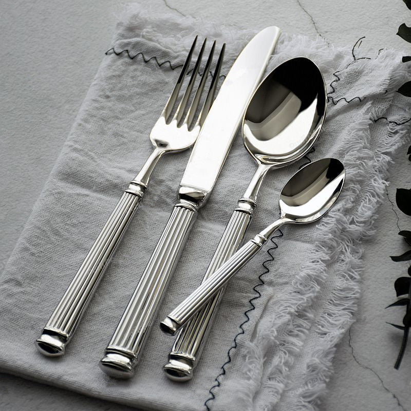 Stainless steel spoon and fork set with Roman-column handles on gray cloth
