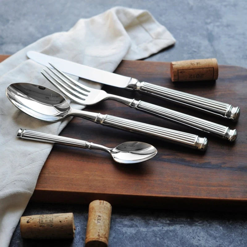Silver-toned flatware set with Roman-column handles: spoon and forks on wooden tray