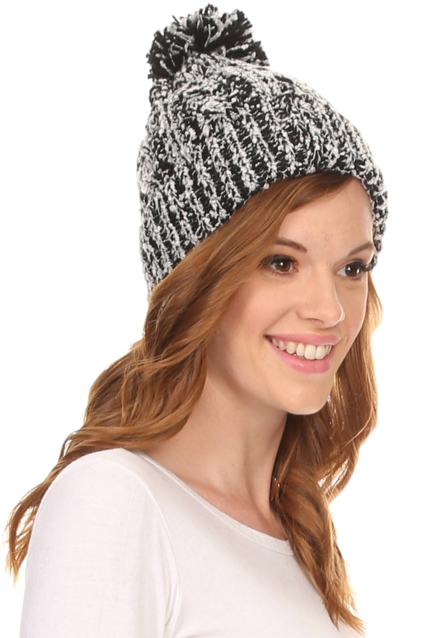 Black-and-white speckled knit beanie with pom pom, worn with side profile.
