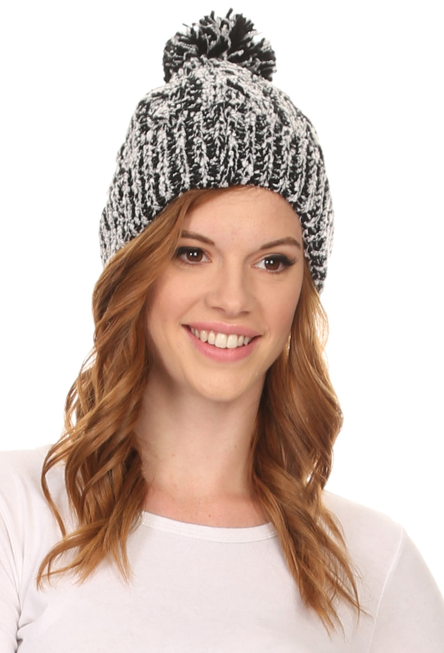 Black-and-white speckled knit beanie with large pom pom, worn by model.