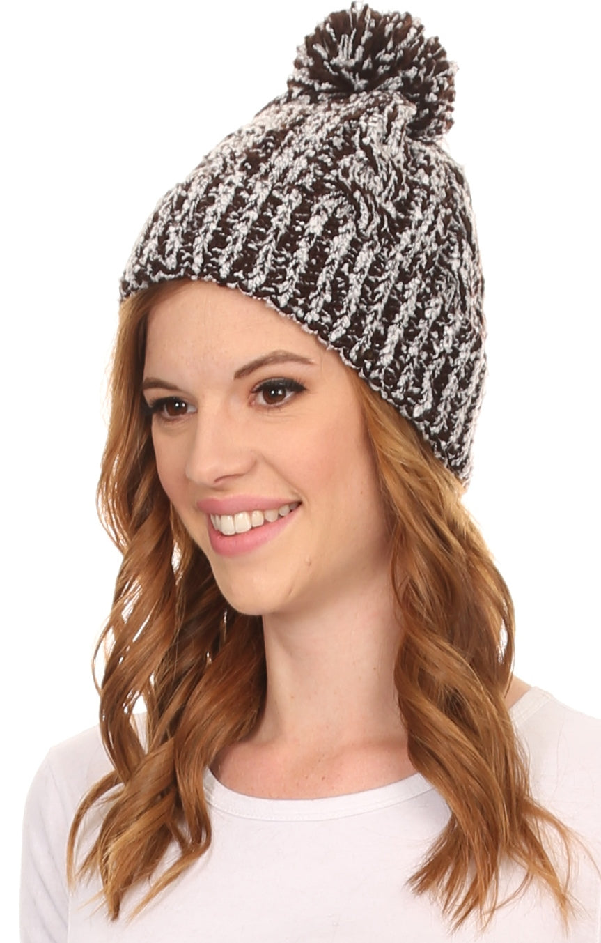Black-and-white speckled knit pom pom beanie hat with ribbed cuff, angled view