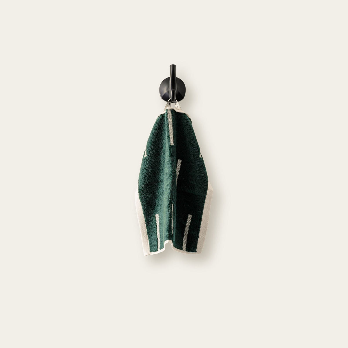 Green cotton towel set with ecru striped trim, folded and hanging on a clip
