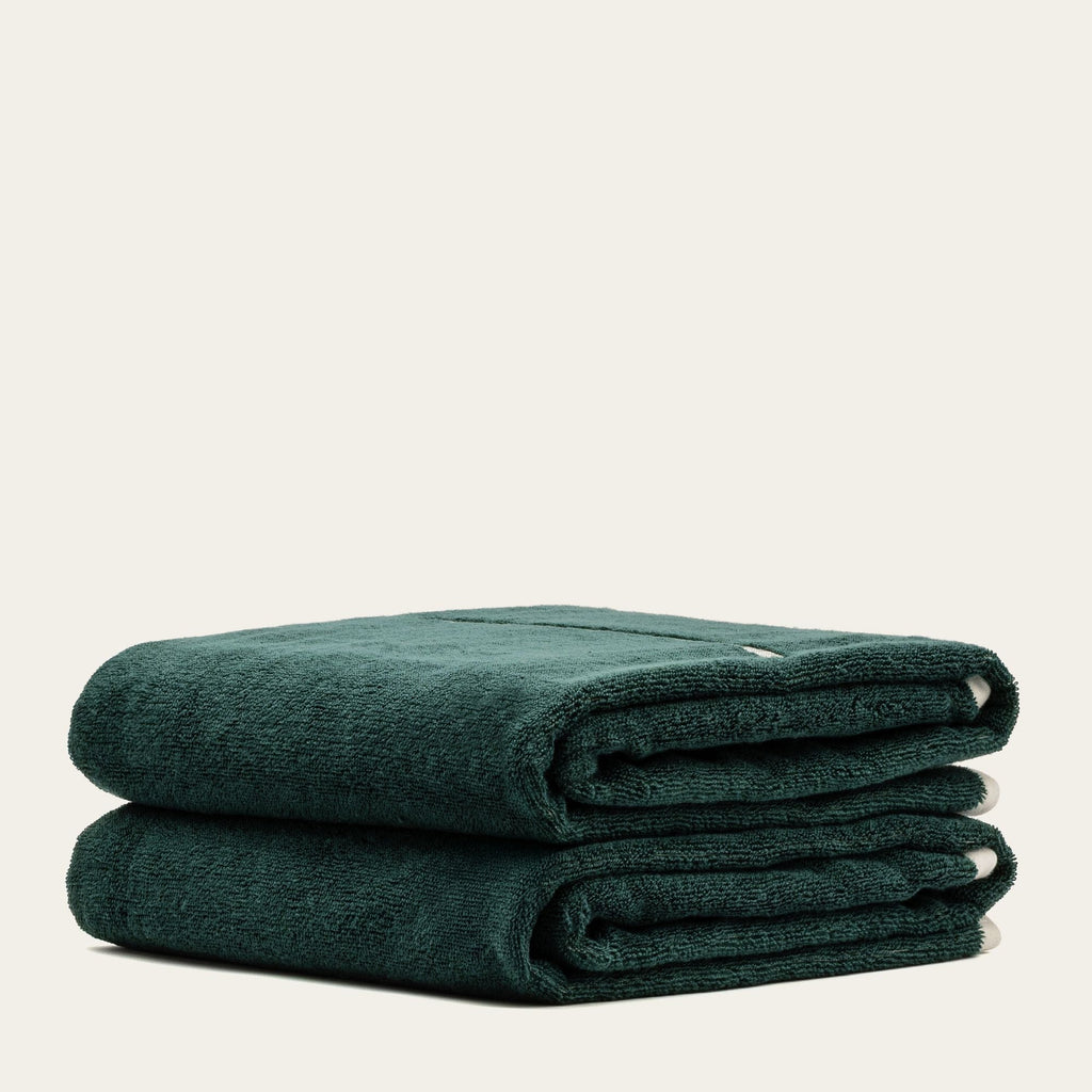 Verdant green cotton towel, folded stack with visible edge seam