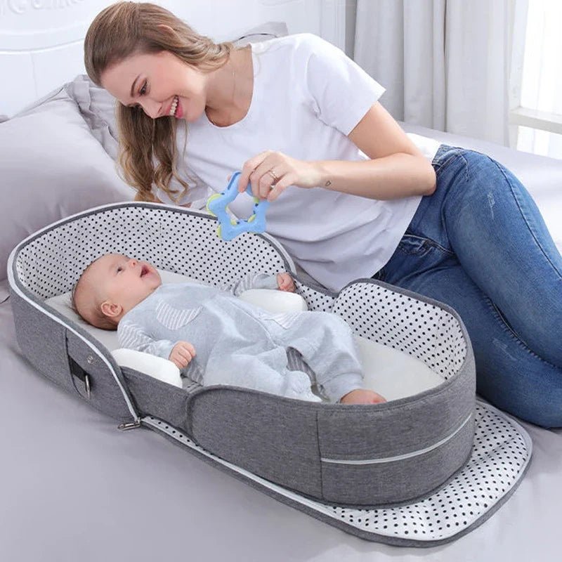 Grey portable baby bassinet with canopy, used indoors with infant inside