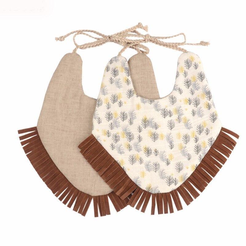 Beige and cream double-layer baby bib with leaf print, fringe edges, and pom trim