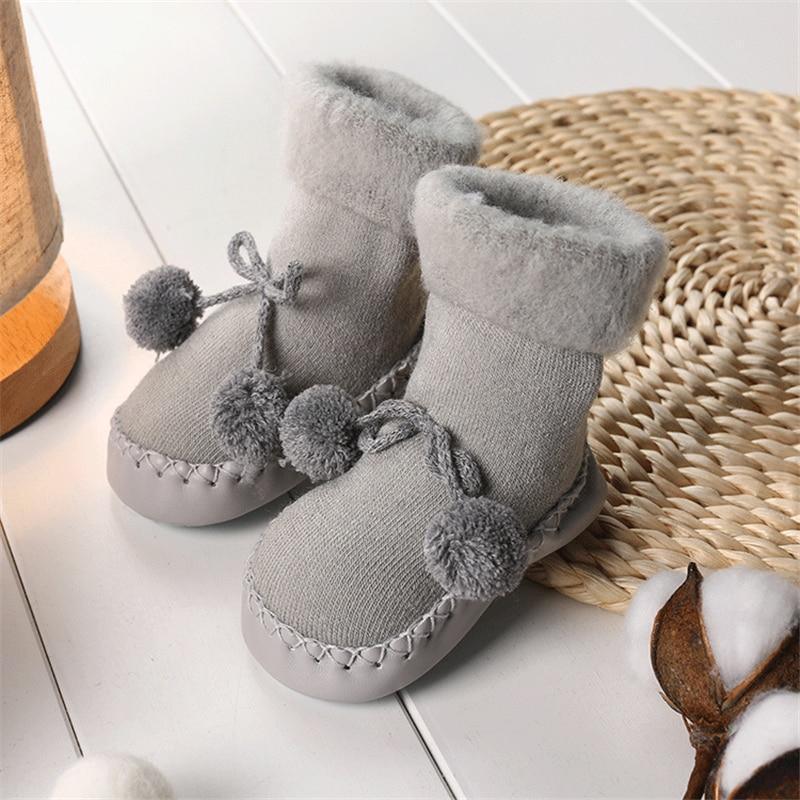 Newborn baby shoes in light gray soft fabric with bow and pom pom side accents