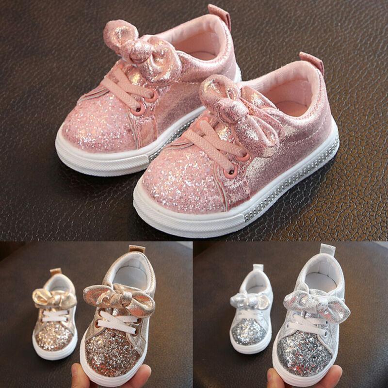 Girls pink glitter sneakers with bow embellishment, lace-up, white rubber sole.