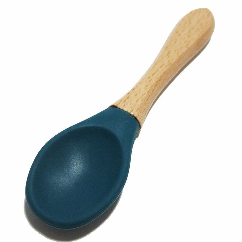 Baby feeding spoon with light wood handle and dark blue silicone tip