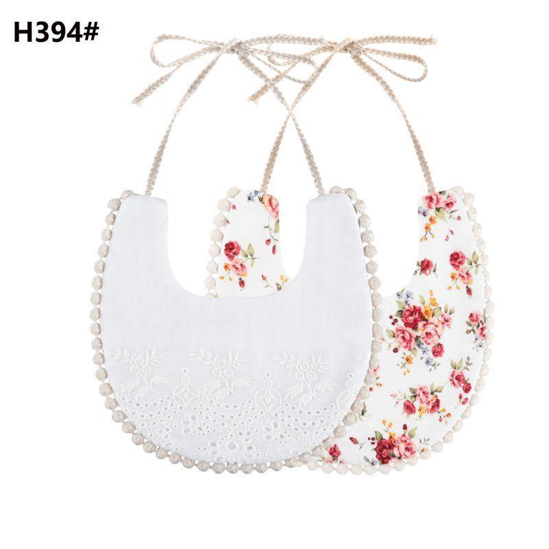 Double-sided cotton baby bib with tassel ties; white eyelet and red floral print.
