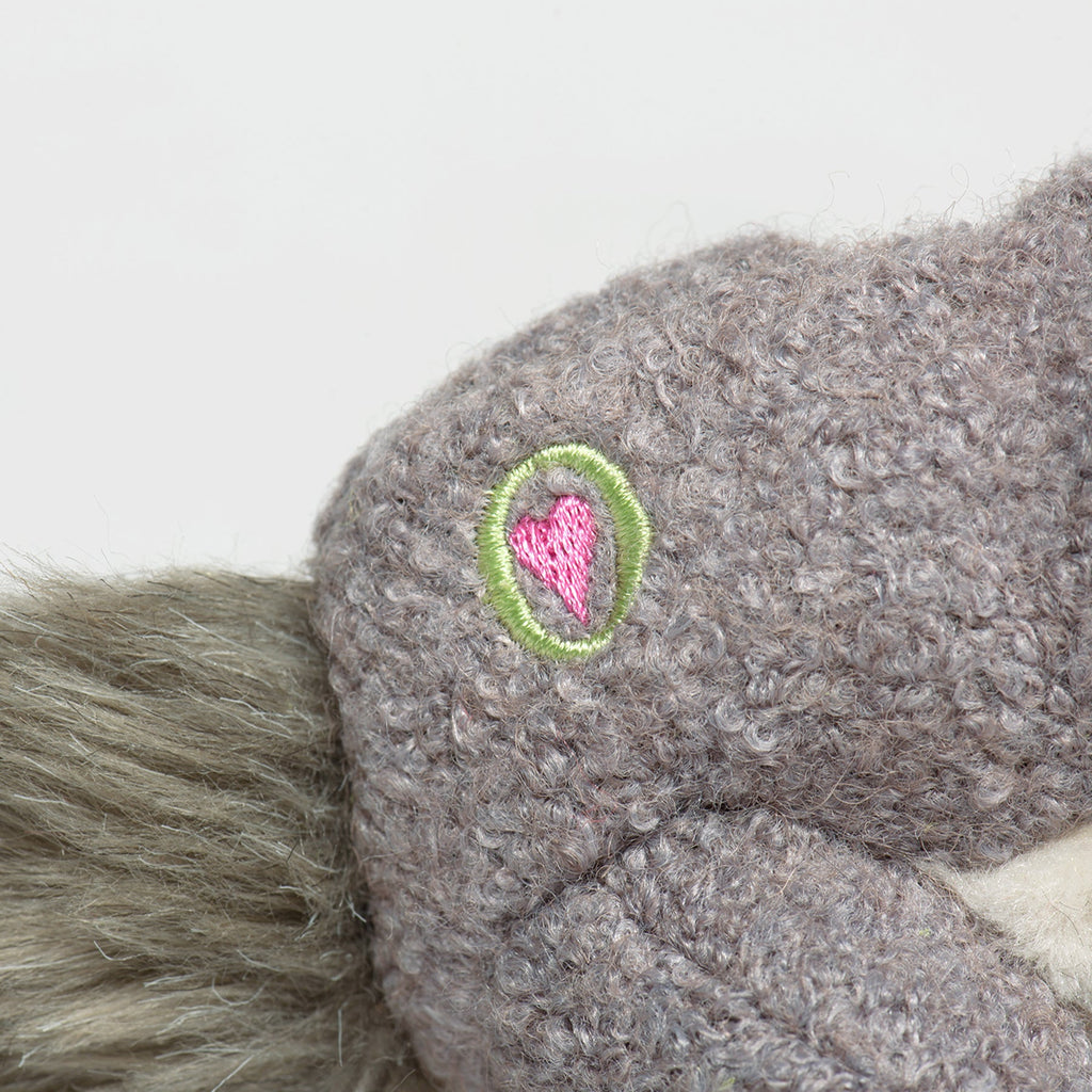 Close-up of gray plush squirrel side with green-and-pink embroidered emblem