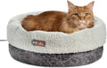 Heated cat bed with a gray base and plush white rim, holding a ginger cat